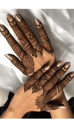 hendi tattoos on the hands of a woman with brown nails and gold nail polish