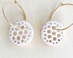 two pairs of white and gold hoop earrings with dots on the front, one has a circular