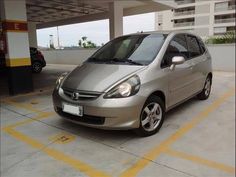 a small silver car parked in a parking lot next to a gas station with yellow lines on the ground