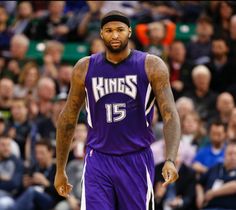 a basketball player in purple is standing on the court with his head turned to the side