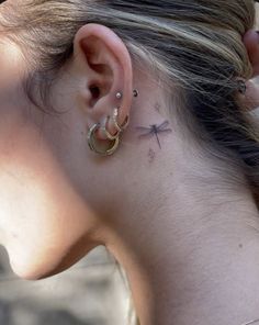 a woman with a dragonfly tattoo on her ear