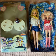 two dolls are sitting next to each other in the box on the bed, one is wearing a sailor moon outfit