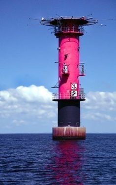 a pink light house sitting on top of the ocean