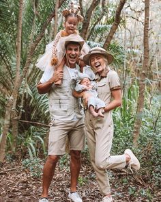 three people are posing for a photo in the woods, one is holding a baby