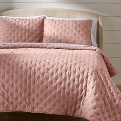 a bed with pink bedspread and pillows on it