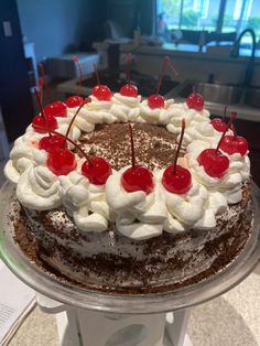 a chocolate cake with cherries and whipped cream