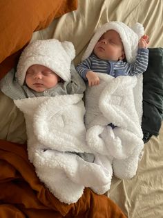 two babies are sleeping in blankets on a bed