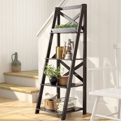 a ladder shelf with plants on it next to a white chair and stairs in the background