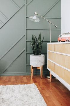 a living room with a white rug and wooden furniture in front of a green paneled wall