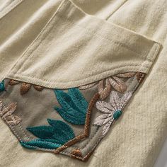 an embroidered pocket on the back of a white t - shirt with blue and green leaves