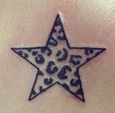 a black and white star tattoo on the back of a woman's shoulder with leopard print