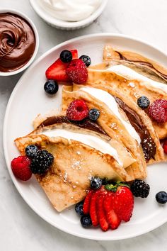 crepes with fruit and chocolate on a white plate