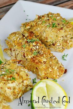 some food on a white plate with lemon wedges