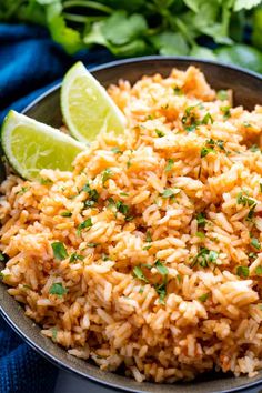 mexican rice in a bowl with lime wedges and cilantro on the side