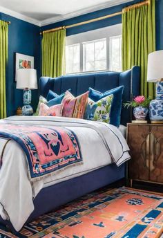 a bedroom with blue walls and green drapes on the windowsills, colorful bedding