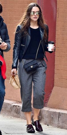 a woman walking down the street with a cup of coffee in her hand and another person holding a purse