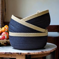 a basket sitting on top of a wooden table next to a bowl filled with fruit