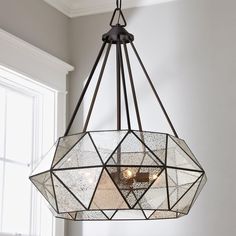 a chandelier hanging from the ceiling in a room with white walls and windows