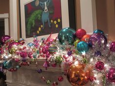 a fireplace mantel decorated with christmas ornaments and tinsel wrapped around the fire place