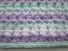 a crocheted blanket with white and purple stripes