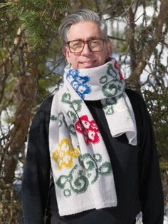 an older man wearing glasses and a scarf with flowers on it is standing in front of a tree