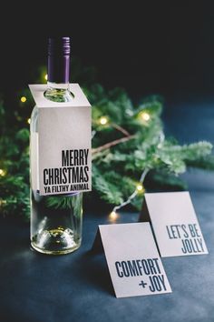 a bottle of alcohol sitting on top of a table next to christmas cards and a tree