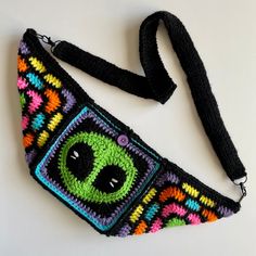 a multicolored crocheted bag with an alien face on it's side