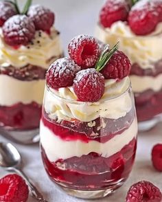 raspberry trifle with whipped cream and fresh berries in small glass dishes next to spoons