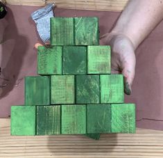 a person is placing green blocks on top of each other