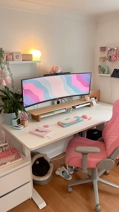 a desk with a computer monitor, keyboard and pink chair