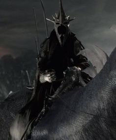 a knight riding on the back of a black horse in front of a dark sky