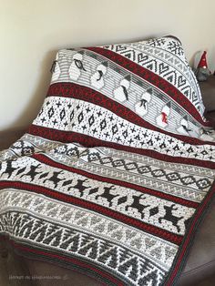 a crocheted blanket sitting on top of a couch next to a christmas tree