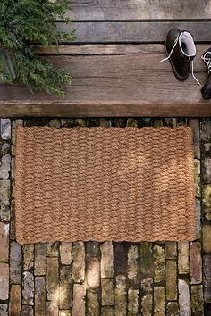 a pair of shoes sitting on top of a wooden bench next to a door mat