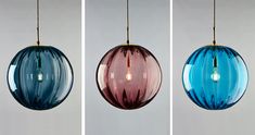 three different shades of blue and pink glass hanging from a ceiling fixture with one light bulb turned on