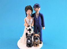 a wedding cake topper with a bride and groom holding two dogs on their lap