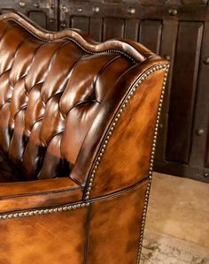 a brown leather couch sitting on top of a stone floor next to a wooden cabinet