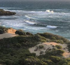 an ocean view from the top of a hill with waves coming in and crashing onto the shore