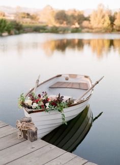 a small boat is tied to the dock with flowers on it's front end