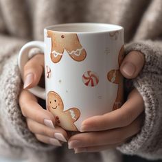 a woman is holding a coffee mug with gingerbreads and candy canes on it