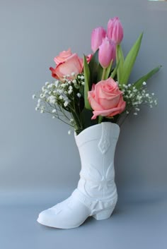 a white boot vase with pink roses and baby's breath