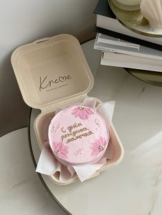 a pink cake sitting on top of a table next to a cupcake in a box