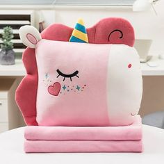 a pink pillow with a unicorn face and stars on it sitting on top of a table