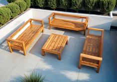 a wooden bench sitting on top of a cement floor next to two tables and chairs