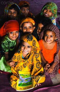 a group of young children sitting next to each other on top of a purple blanket