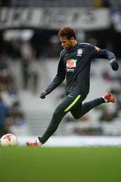 a man kicking a soccer ball on top of a field