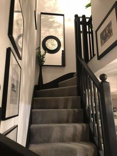 a staircase with pictures on the wall and a clock mounted to it's side