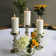 three candles are sitting on a table with flowers