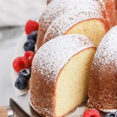 a bundt cake with powdered sugar and berries on the side