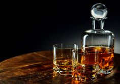 two glasses and a decanter on a wooden table