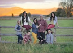 a family posing for a photo in front of a fence